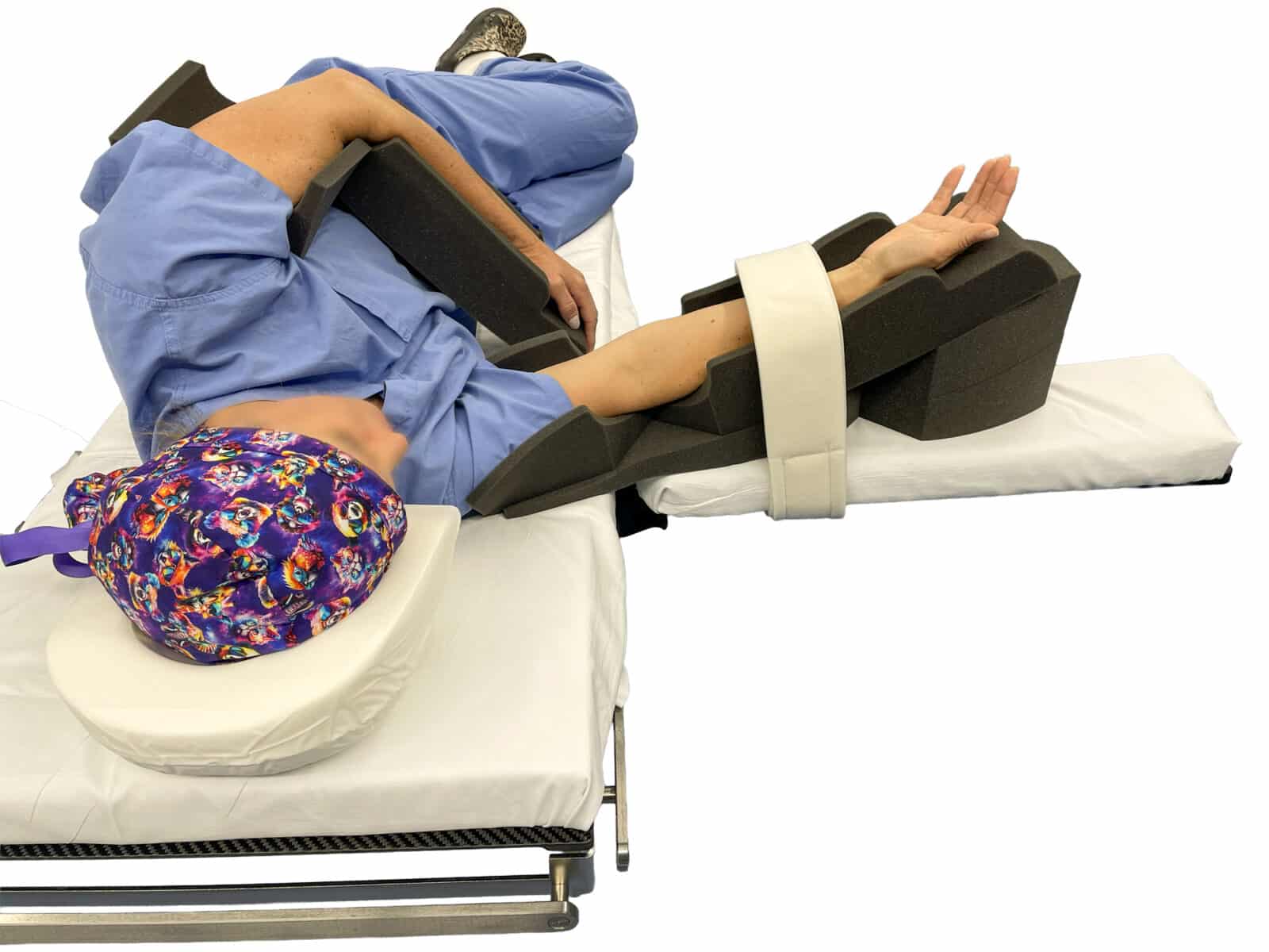 A patient in the lateral position on a surgical table, their arm supported by a dark gray foam cradle with a strap.
