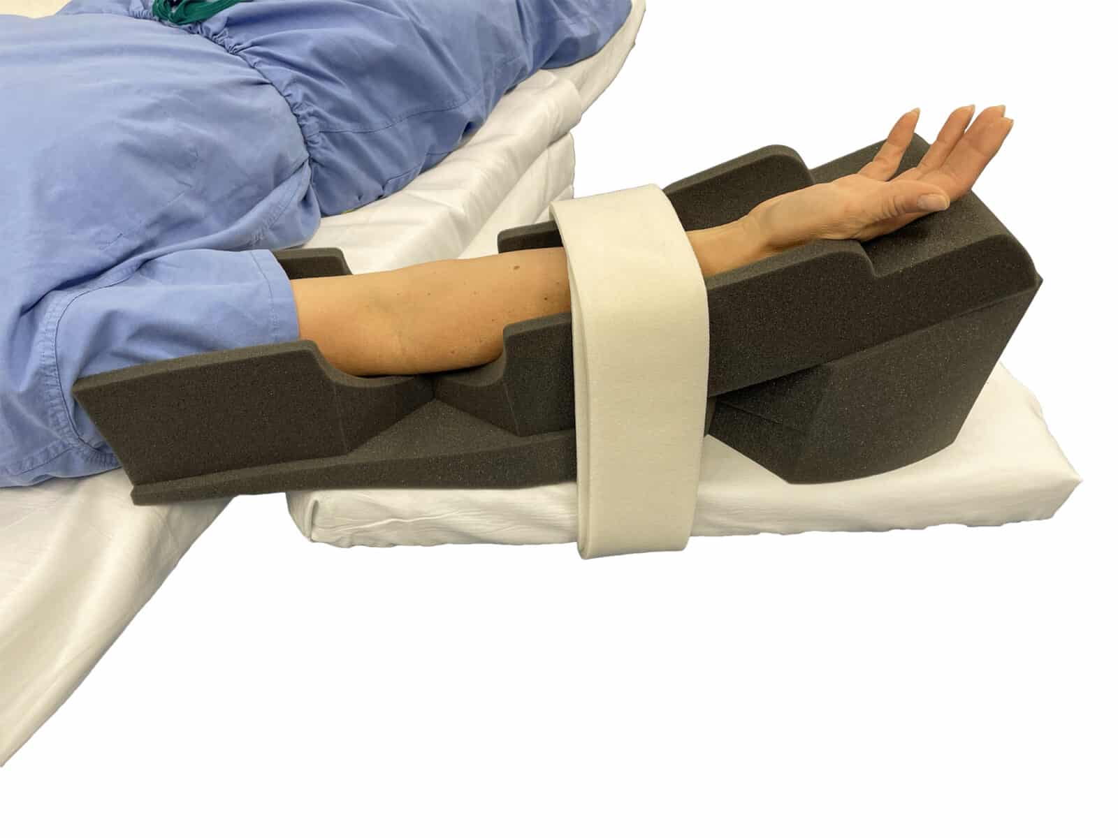 A patient's arm resting in a dark gray foam cradle, secured by a white strap, while in the supine position.