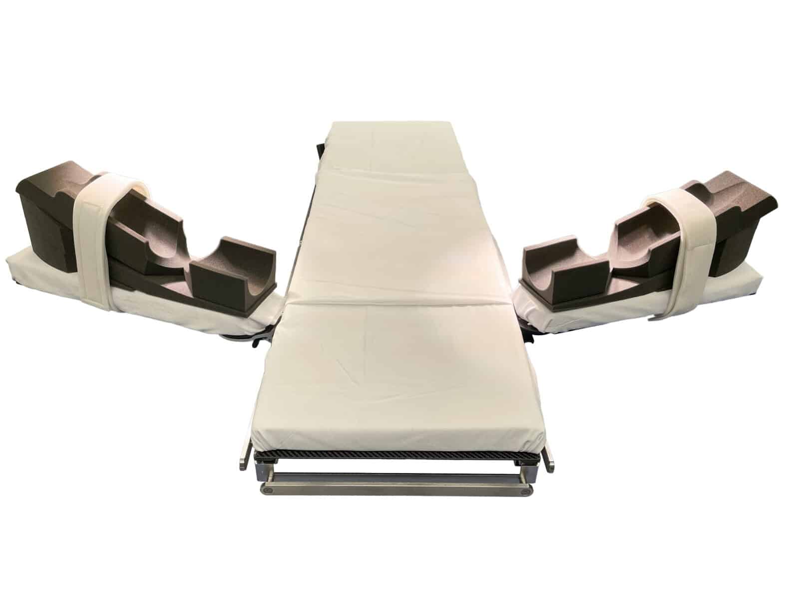 Two charcoal foam extremity cradles with white straps attached to either side of an empty surgical operating table.