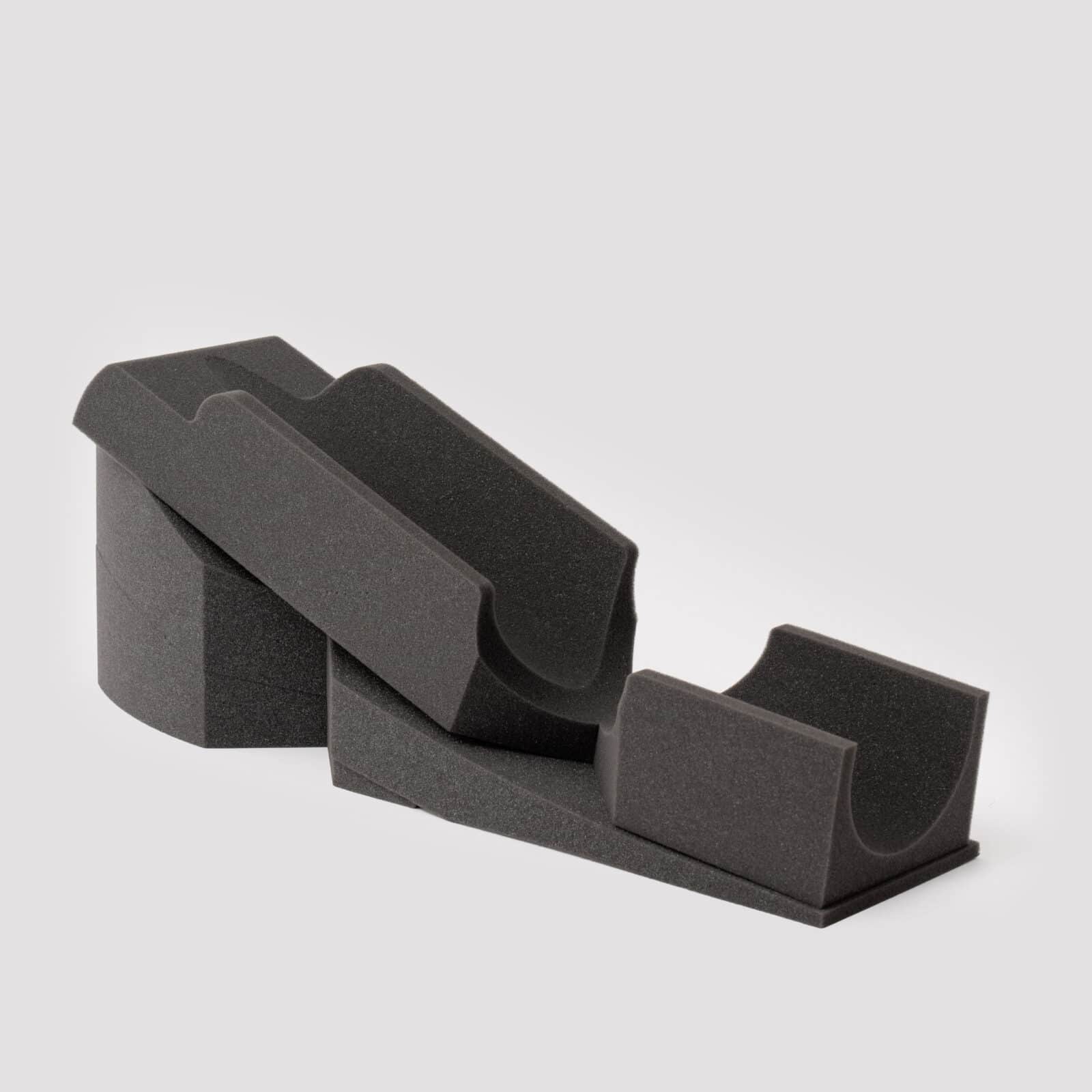 EEC Product Full A multi-part surgical positioner in dark gray foam, with two U-shaped cradles for stable extremity support.